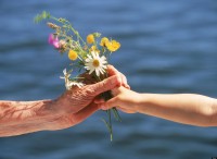 Grandchild offering small bouquet of summer wild flowers to grandmother